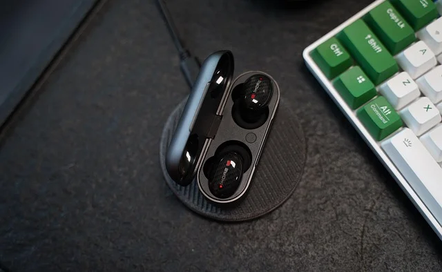 Zatyczki douszne w etui obok klawiatury na biurku