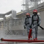 Strażacy w odzieży ochronnej podczas akcji gaśniczej na terenie zakładu