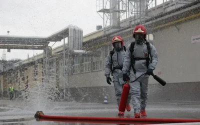 Strażacy w odzieży ochronnej podczas akcji gaśniczej na terenie zakładu