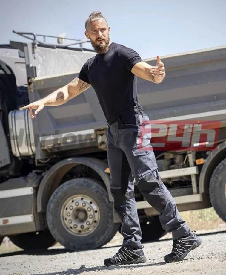 Mężczyzna w spodniach roboczych na tle ciężarówki budowlanej